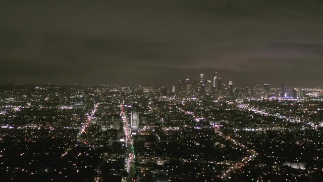 AERIAL: View over Los Angeles at Night with Wilshire Boulevard Glowing Streets and City Car Traffic Lights 