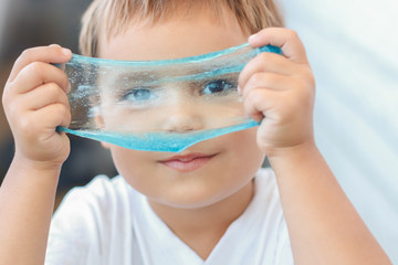 The kid plays with a toy called slime, stretches and sculpts fun on his face. The child is having fun with a creative scientific experiment