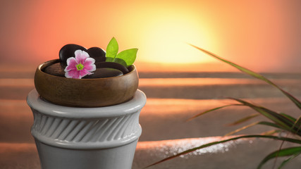 Blume und Steine in der Holzschale am Meer bei Sonnenuntergang
