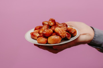 The guy holds in his hands dates (on a pink background). Ramadan