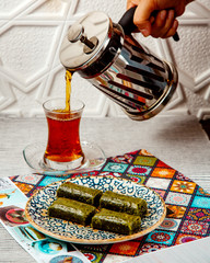 woman pouring black tea from french press served with turkish dessert