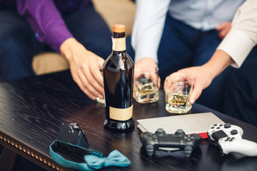 Obraz na płótnie Canvas three men drink whiskey and play video games