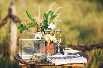 on the table are the attributes of the wedding ceremony: a box with rings, glasses with wine, an embroidered towel, a bouquet of flowers