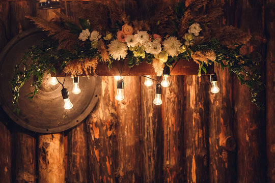 The wooden wall is decorated with electric lamps and flowers. wedding decorations rustic