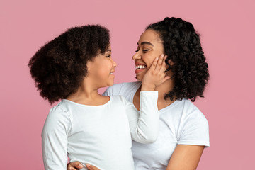 Smiling cute black girl tenderly touching face of her loving mother