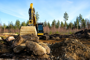 Yellow excavator building a road deep in the forest. Rusko, Finland.