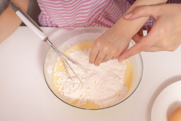A little cute girl and her mother preparing the dough in the kitchen at home, happy family concept