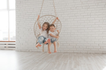 little children sit in a circular rope swing