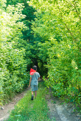 Obraz premium A young boy walks along the path to the forest in the summer on vacation