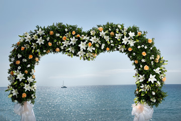 Decorazione floreale a forma di cuore di altare per una cerimonia al mare, sfondo cielo mere e una...