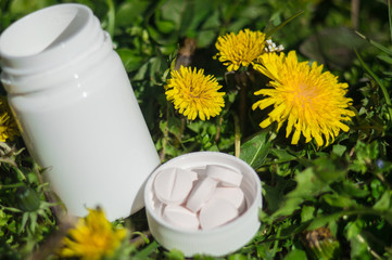 Obraz na płótnie Canvas White pills in the grass with flowers