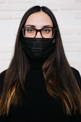 brunette girl in glasses for vision correction is protected from a viral infection: coronavirus. A...