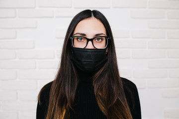 brunette girl in glasses for vision correction is protected from a viral infection: coronavirus. A...