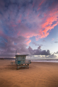 The skies explode in color during sunset over a lifeguard stand in Hermosa Beach, California.