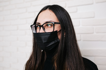 brunette girl in glasses for vision correction is protected from a viral infection: coronavirus. A...