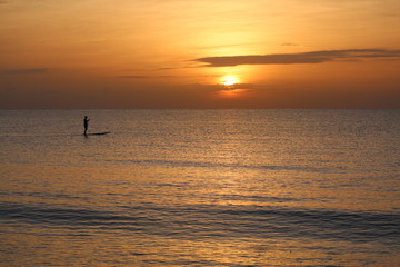 A man in silhouette goes Stand-up Paddleboarding as the sun rises over the Atlantic Ocean in Delray Beach, Florida.