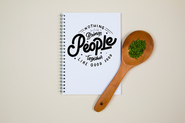 Wooden ladle with some herb spice and a blank notebook page