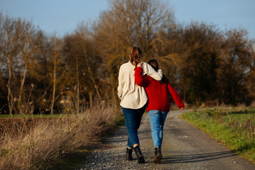 Two sisters walk on the road on a sunny day