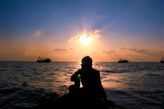 silhouette of man sitting in boat at Indian Ocean during a vibrant sunset 