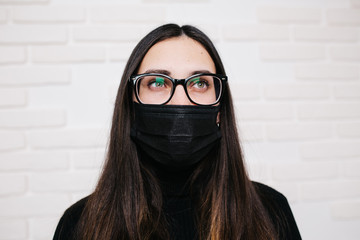 brunette girl in glasses for vision correction is protected from a viral infection: coronavirus. A...