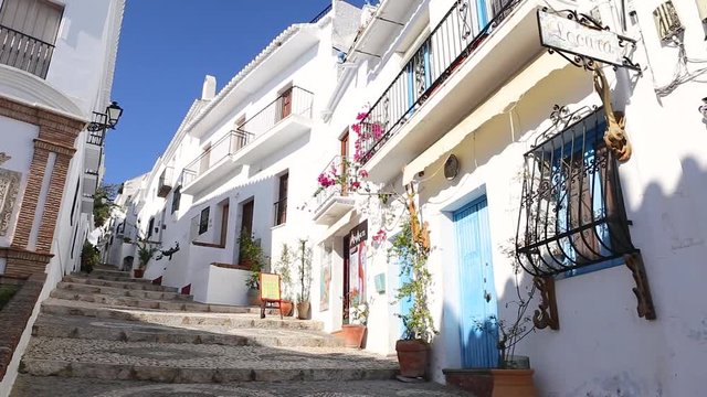 Picturesque narrow street with white houses , beautiful flowers and souvenir shop in village of Frigiliana, in south of Spain.
