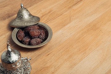 Dates fruit and silver coffee cup on wooden table. The Muslim feast of the holy month of Ramadan. 
