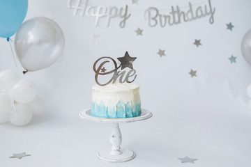 Festive background decoration for birthday celebration with gourmet cake and blue balloons in studio, cake smash first year concept