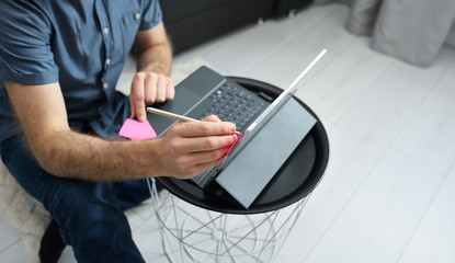 Young man in casual clothes sitting on floor and working on his laptop computer at home. Stay home and work online. Quarantine concept, panoramic banner