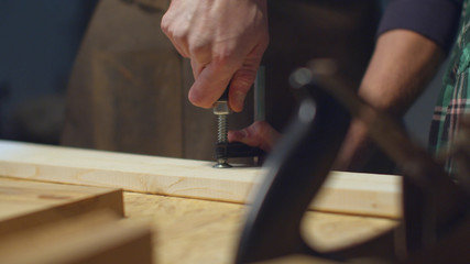 The carpenter secures the bar with a clamp