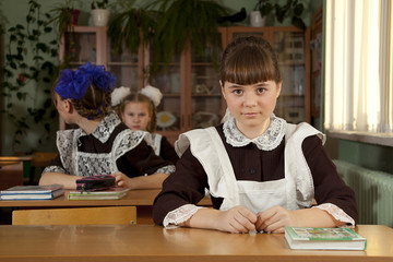 schoolgirl sitting at the table in the classroom