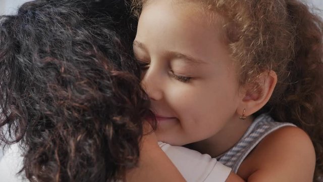Happy family concept. Cute affectionate daughter adopted little child baby girl hugs parent's mother mother with closed eyes,adorable child daughter hugging mom cuddle enjoying a tender sweet moment