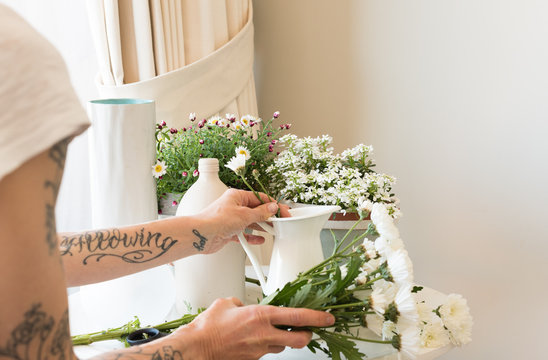 Cropped Hands Of Mature Woman Arranging Flowers In Vase