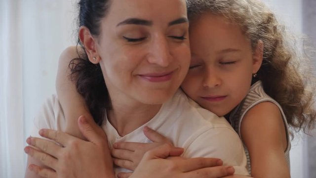 Happy family concept. Cute affectionate daughter adopted little child baby girl hugs parent's mother mother with closed eyes,adorable child daughter hugging mom cuddle enjoying a tender sweet moment