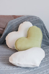 white and olive heart pillows on a sofa