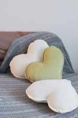 white and olive heart pillows on a sofa