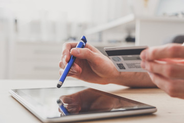 Man using pc tablet with stylus and credit card at the table, shopping online