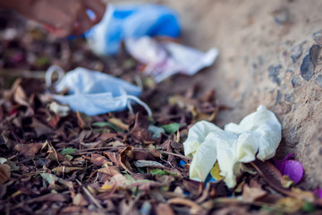 Used medical face masks and gloves on the ground outdoor. Environmental pollution concept