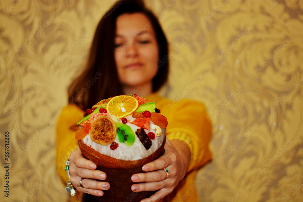 Wall mural easter. beautiful brunette girl in a yellow sweater holds fruit easter hands, with place for text, e