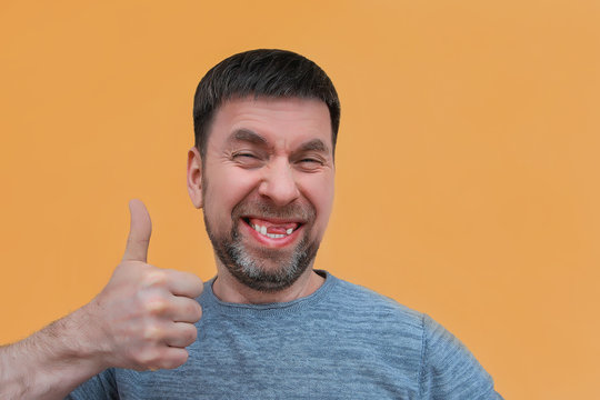 cheerful charismatic bearded young man with no front upper teeth gives a thumbs up