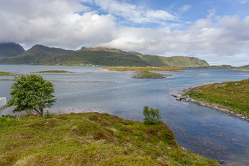 Norwegian fjord and mountains surrounded by clouds, ideal fjord reflection in clear water. selective focus.