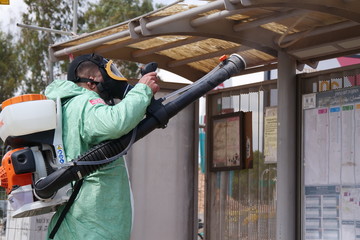 A person disinfects a bus stop from the Corona virus.
