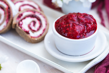 Raw raspberry jam in a white cup with raw raspberry rolls. Vegan food.