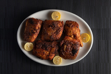 Fried Fish with Lemons on a white dish on a dark background
