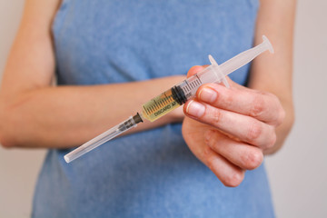 A young, pregnant woman holds a syringe in front of her