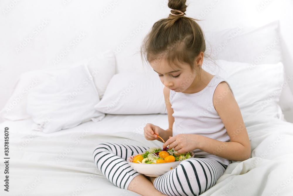 Wall mural Cute little girl with fruits and vegetables.