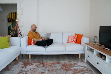 man working in quarantine days sitting on sofa at home happily viewing computer leptop