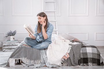 Young beautiful woman reading a book on the bed.