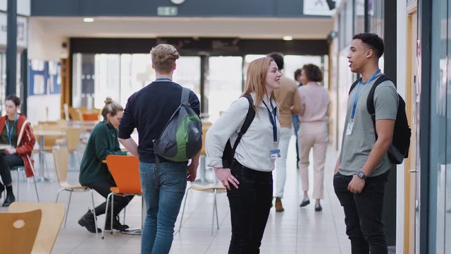 College student couple meeting and talking in busy communal campus building - shot in slow motion