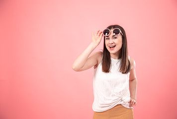 Portrait of a young woman with glasses on a pink background.