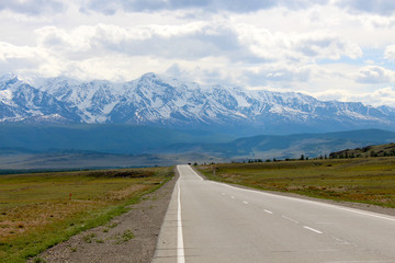 Road to the mountains with snowy peaks and steppe
